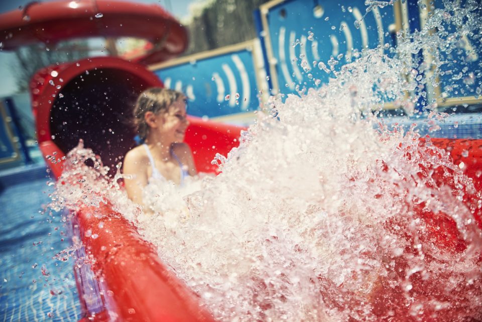 Little girl having fun sliding in water park
